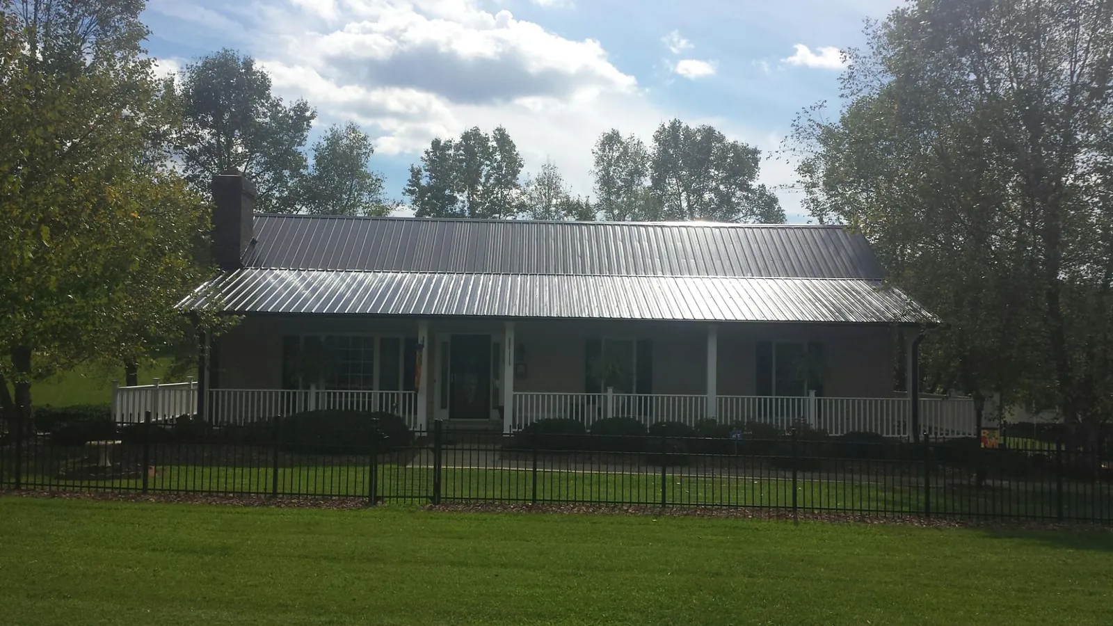 Gray metal roof on a brick ranch with a full width front porch — Gutter Guard Installation work by our crew in Pownal