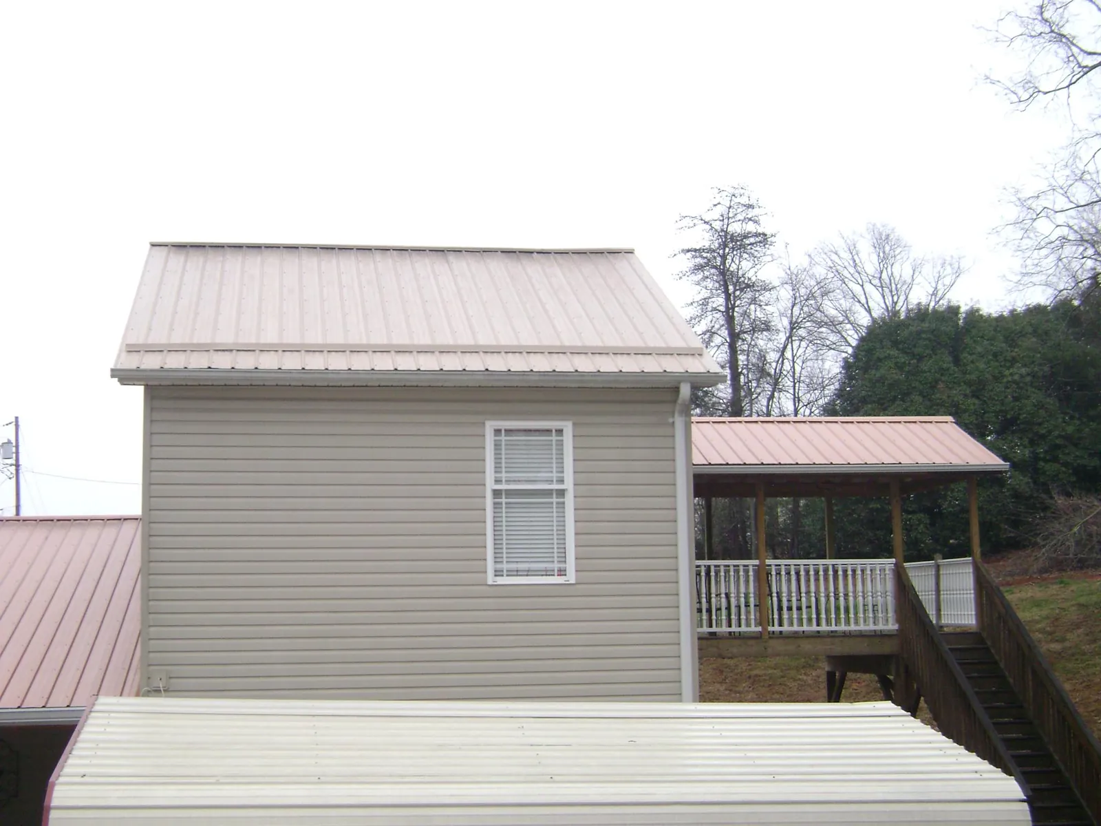 Tan metal roofs on a two story addition and attached porch, from a Roof Replacement job in Pownal